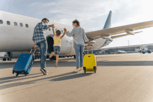 Family boarding airplane with colorful luggage.